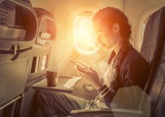 Woman sitting at airplane and looking to mobil phone.