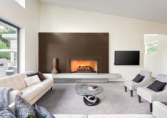 Beautiful furnished living room in luxury home with fireplace, tv, couches, chairs, and glimpse of backyard patio